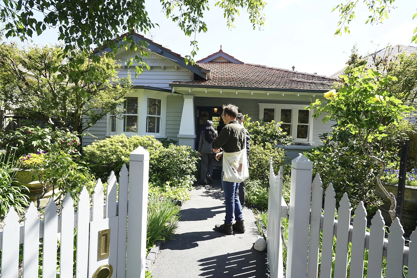 带白色围栏的住宅门前，一人走向房屋入口